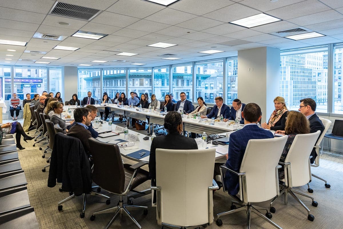 Men and women sit at a conference table discussing environmental, social and governance, or ESG, frameworks at an GSmax forum.
